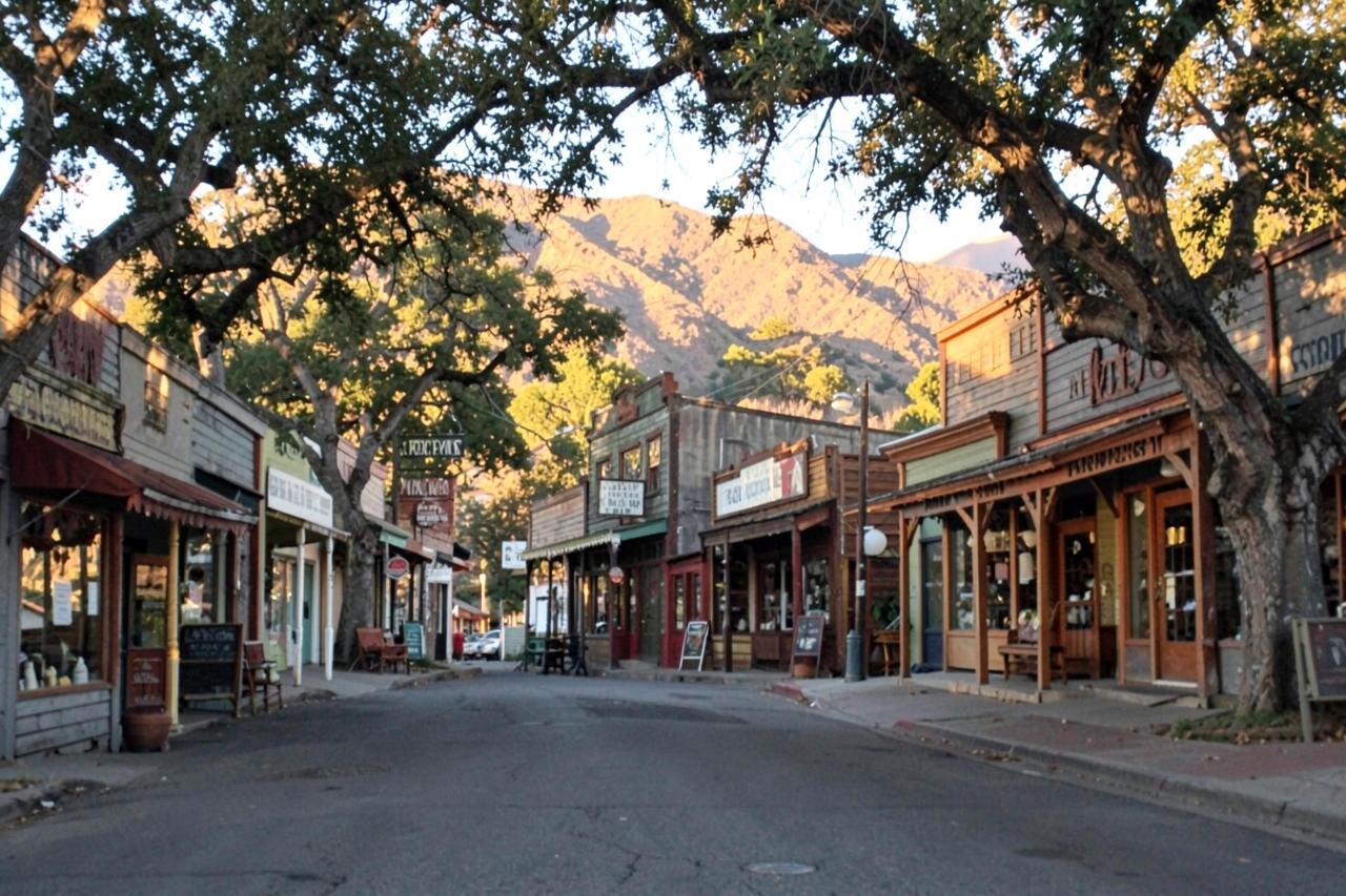 Jamestown's main street of wooden false-front shops under oak trees with golden hills behind